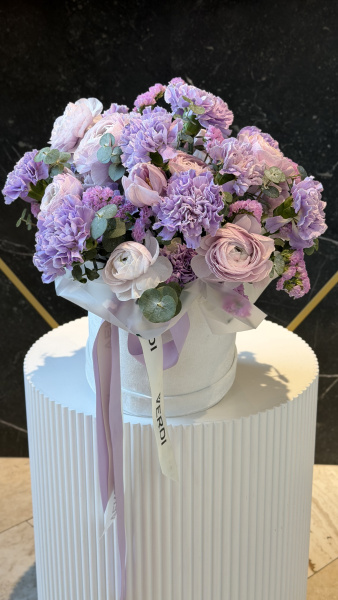 Коробка з бузкових гвоздик, ніжно-рожевих ранункулюсів та статиці